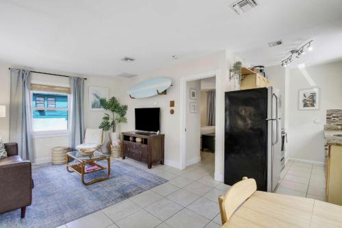 a living room with a table and a black refrigerator at Cottage 3 on Penn - Pool in West Palm Beach