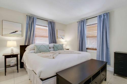 a bedroom with a large bed with blue curtains at Cottage 3 on Penn - Pool in West Palm Beach