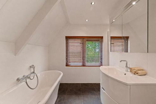 a white bathroom with a tub and a sink at Villa Verano in Noordwijk aan Zee