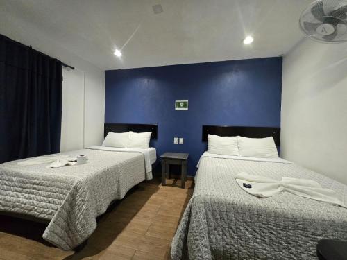 two beds in a room with a blue wall at Hotel Santo Domingo in Comitán