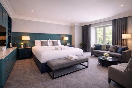 a bedroom with a bed and a living room with a couch at The Regency Hotel in Solihull