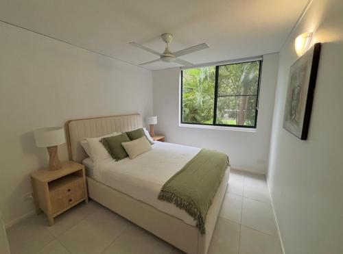a white bedroom with a bed and a window at Rainbow Beach Resort overlooking Pool in Rainbow Beach