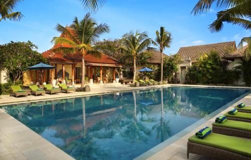 サヌールにあるSudamala Resort, Sanur, Baliのヤシの木と椅子が備わるリゾートのプールを利用できます。