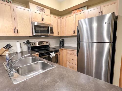 a kitchen with a stainless steel refrigerator and a sink at Top Floor Beautiful Mountain Views! 2 Bed 2 Bath in Canmore