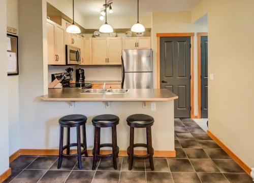 a kitchen with three bar stools at a counter at Top Floor Beautiful Mountain Views! 2 Bed 2 Bath in Canmore