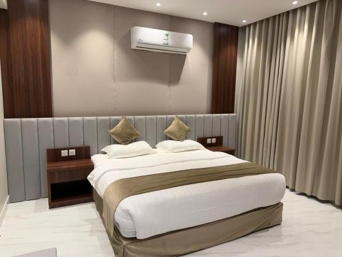 a bedroom with a large bed and a air conditioner at متسع للشقق المخدومة - اقتصادي in Hail