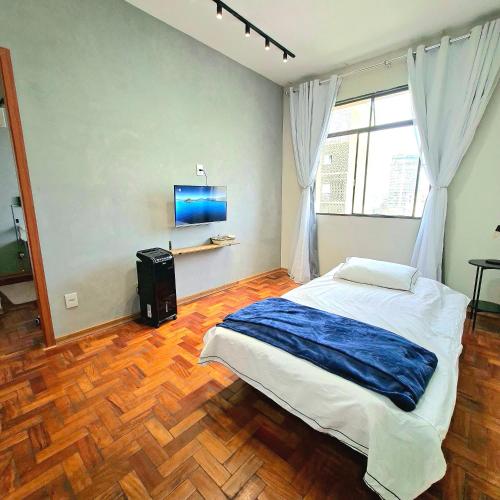 a bedroom with a large bed and a wooden floor at Centro de BH, Ar-Condicionado, Wi-Fi Rápido, 6min Rodoviária, Portaria 24h in Belo Horizonte