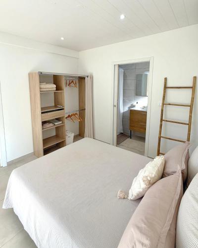 a bedroom with a white bed and a closet at Le Cocon du Cos in Ducos