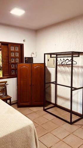 a room with a bed and a kitchen with a refrigerator at Refúgio do Ipê Rosa in Tubarão