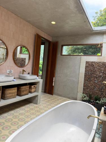 a bathroom with two sinks and two mirrors at First Light Villa at Lipah Beach, Amed in Amed