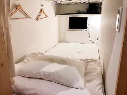 a small room with a bed with white sheets and a tv at Cafe&Hostel Kimi to Ichigo in Osaka