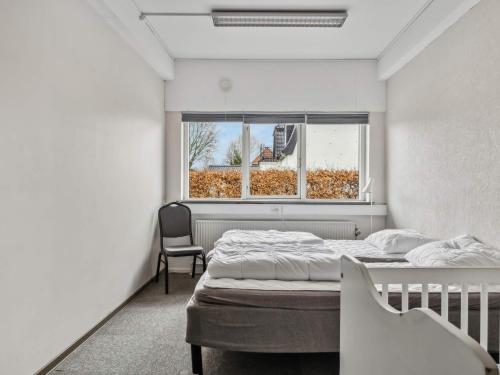 a bedroom with a bed and a window and a chair at Expansive Villa near Ribe in Skærbæk