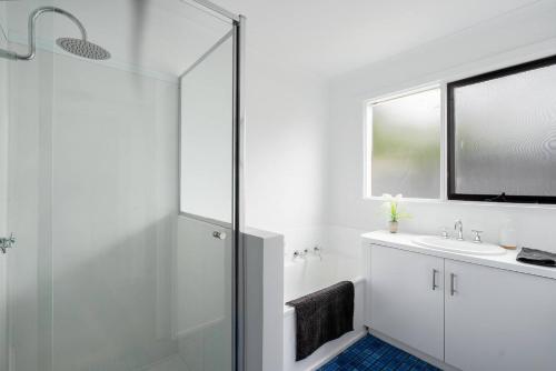 a white bathroom with a shower and a sink at 550m to Beach, SPA and Large Backyard , Sleep 9 in Ocean Grove