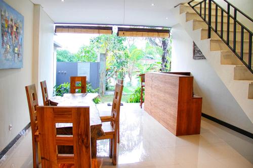 a dining room with a table and chairs and a staircase at Ryanbagus Guest House in Canggu