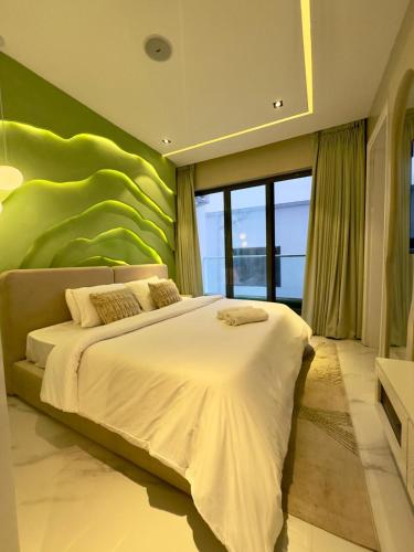 a bedroom with a large bed with a green wall at Luxury 2 Bedroom Apartment with 2 Private Patios in Lekki Phase 1 in Lekki