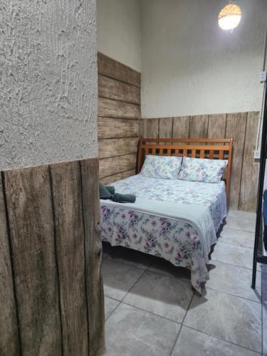 a bedroom with a bed with a wooden wall at Pousada Casa da arara Suite 106 in Saquarema