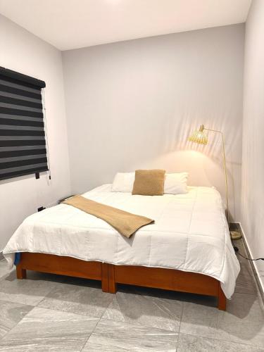 a bedroom with a bed with white sheets and a lamp at Comfort stay Mazatlan in Mazatlán