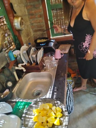 a woman standing in a kitchen with a sink at Nostalgia Camping Home 1 in Selemadeg