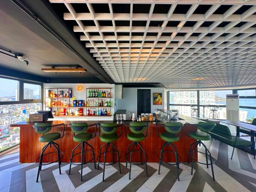 a bar with green bar stools in a restaurant at Odin Hotel Quy Nhon in Quy Nhon