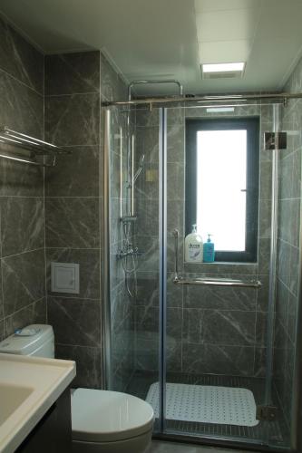 a bathroom with a shower with a toilet and a window at Miri apartment in Kunming