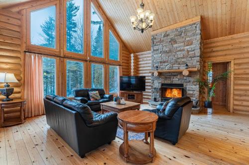 a living room with leather furniture and a stone fireplace at Fiddler Lake Resort - Deer 80 in Mille-Isles