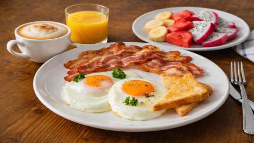 a plate of eggs bacon and toast and a cup of coffee at Sokchea Kampot Hotel in Kampot