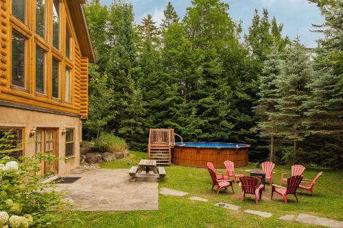 a patio with chairs and a hot tub in a yard at Fiddler Lake Resort - Deer 41 in Mille-Isles