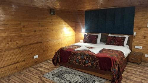 a bedroom with a large bed in a wooden wall at Birdsong pahalgam in Pahalgām
