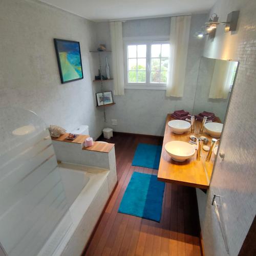 a bathroom with two sinks and a tub and two mirrors at appartement dans villa aquarelle in Biguglia
