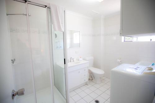 a white bathroom with a shower and a toilet at Trinity Beach Pacific in Trinity Beach