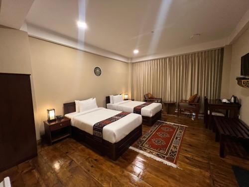 a hotel room with two beds and a table at Taktshang Paradise in Paro