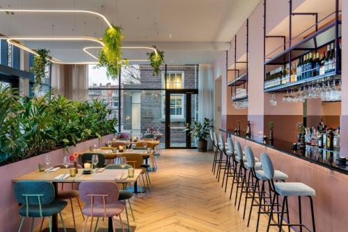 a restaurant with tables and chairs and a bar at The Rebyl, Nijmegen, a Tribute Portfolio Hotel in Nijmegen