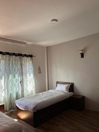 a bedroom with a bed and a window at Yatra Chhen in Bhaktapur