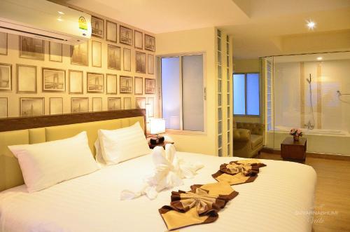 a bedroom with a bed with white sheets and pictures on the wall at Suvarnabhumi Ville Airport Hotel in Lat Krabang