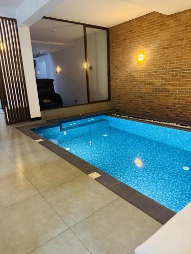 a swimming pool in a room with a brick wall at Mack Win Villa in Pannipitiya