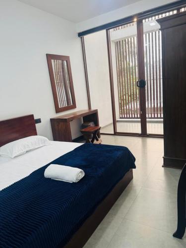 a bedroom with a bed with a blue blanket and a window at Mack Win Villa in Pannipitiya