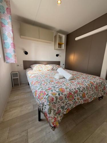 a bedroom with a large bed with a floral blanket at Chez Angel et Flo - E27 - Mobil home tout confort - 15 minute Europa Park - terrasse privée in Boofzheim