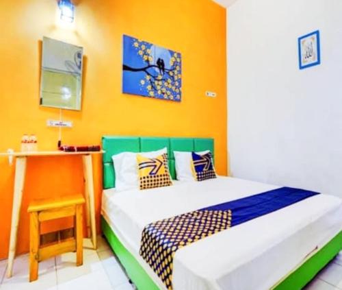 a bedroom with a bed and a table with a stool at Edotel Tebe Syariah in Rampal