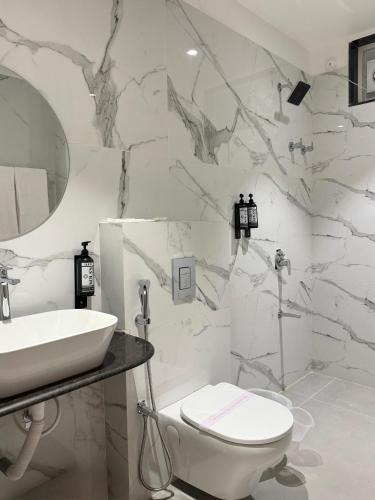 a white bathroom with a sink and a toilet at Kolas Grand - Hotel and Convention Center in Warangal
