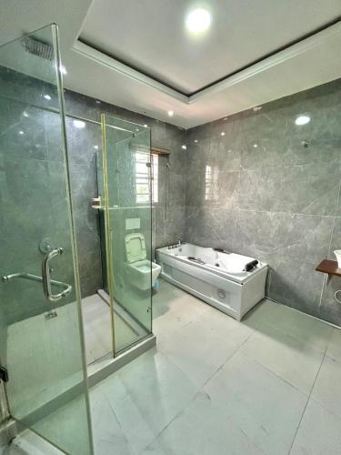 a bathroom with a shower and a tub and a sink at City Xcape Niche in Lekki