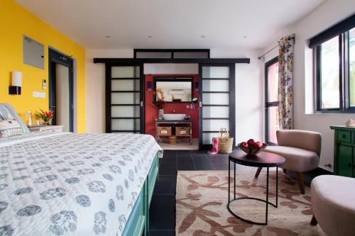 a bedroom with a bed and a chair and a table at Owl and the Pussycat Hotel & Restaurant in Unawatuna