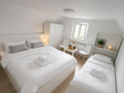 a white bedroom with two beds and a table at Gemütliches Haus für Familien bis zu 7 Personen mit Parkplatz und ruhiger Lage in Selzthal