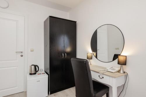 ein Schreibtisch mit Spiegel und einem schwarzen Schrank in der Unterkunft Hotel Azzurro in Herceg-Novi