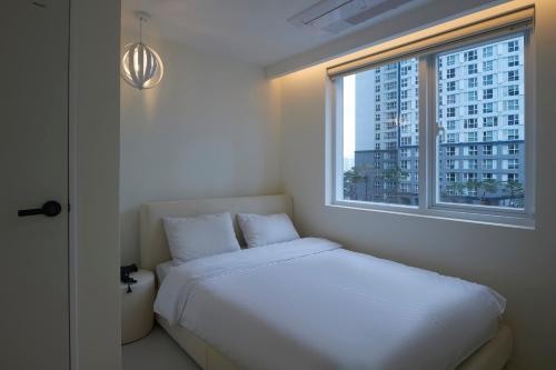 a bedroom with a white bed and a window at Canvas Hostel in Busan
