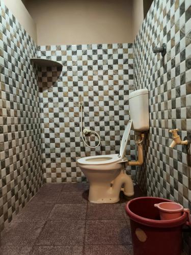 a bathroom with a toilet in a checkered wall at janaki Homestay in Gokarna