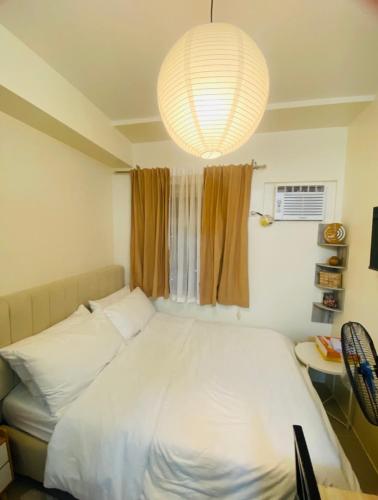 a bedroom with a large white bed and a chandelier at Casa Ona in Manila