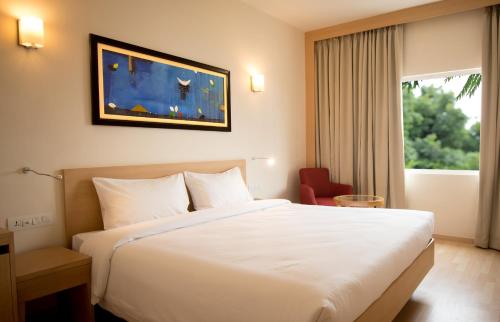 una camera d'albergo con un grande letto bianco e una finestra di Red Fox Hotel, Trichy a Tiruchchirāppalli