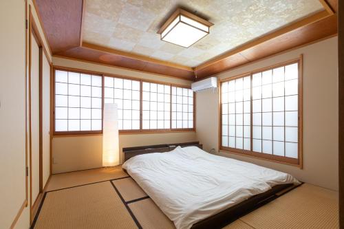 a bedroom with a bed in a room with windows at R House 川越 in Kawagoe