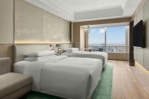 a hotel room with three beds and a television at Suzhou Marriott Hotel in Suzhou