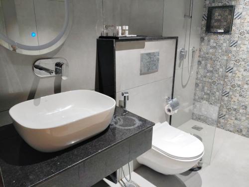 a bathroom with a white sink and a toilet at Ramanashree California Resort in Yelahanka